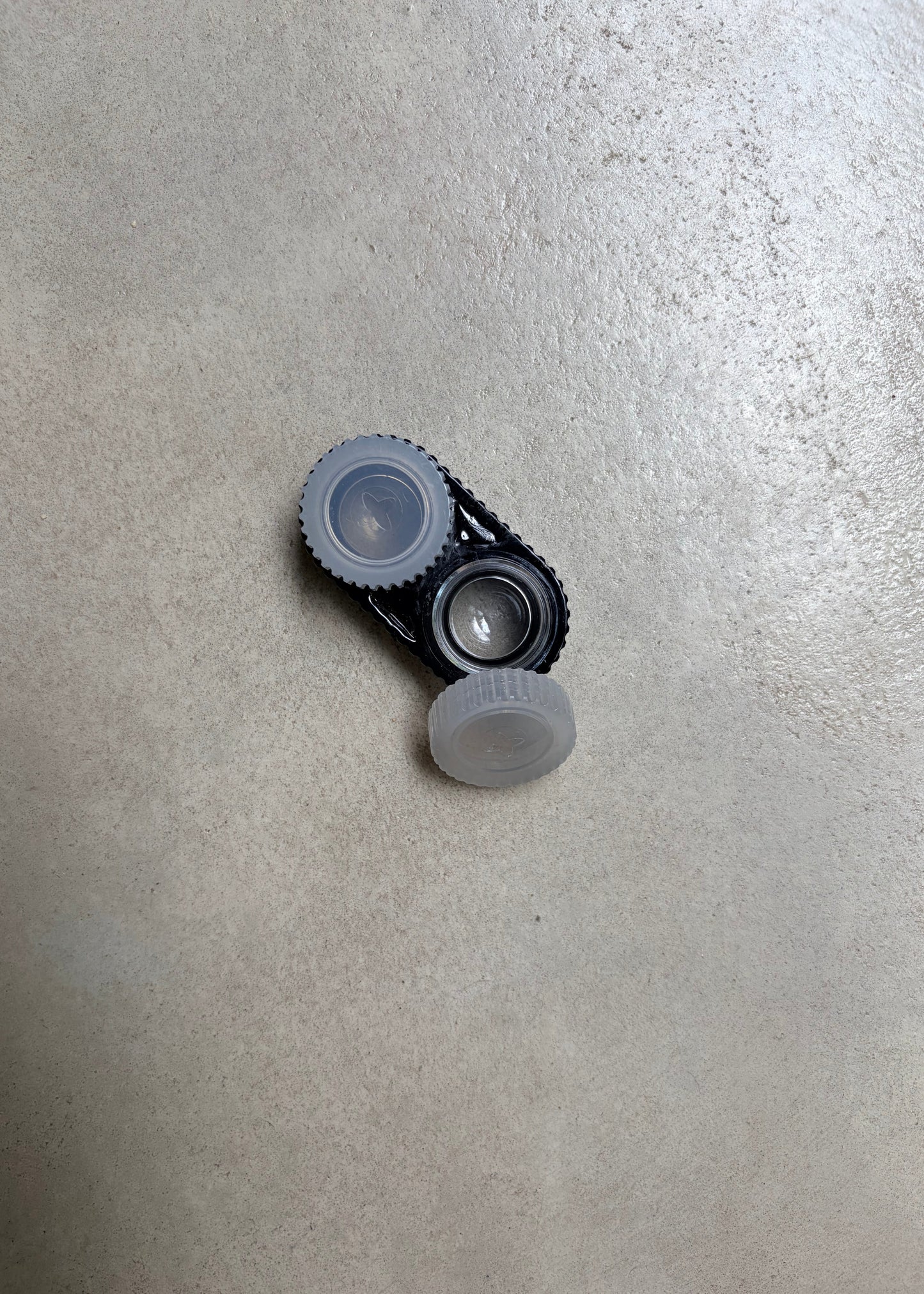 A black contact lens case with white caps, seen from the top
