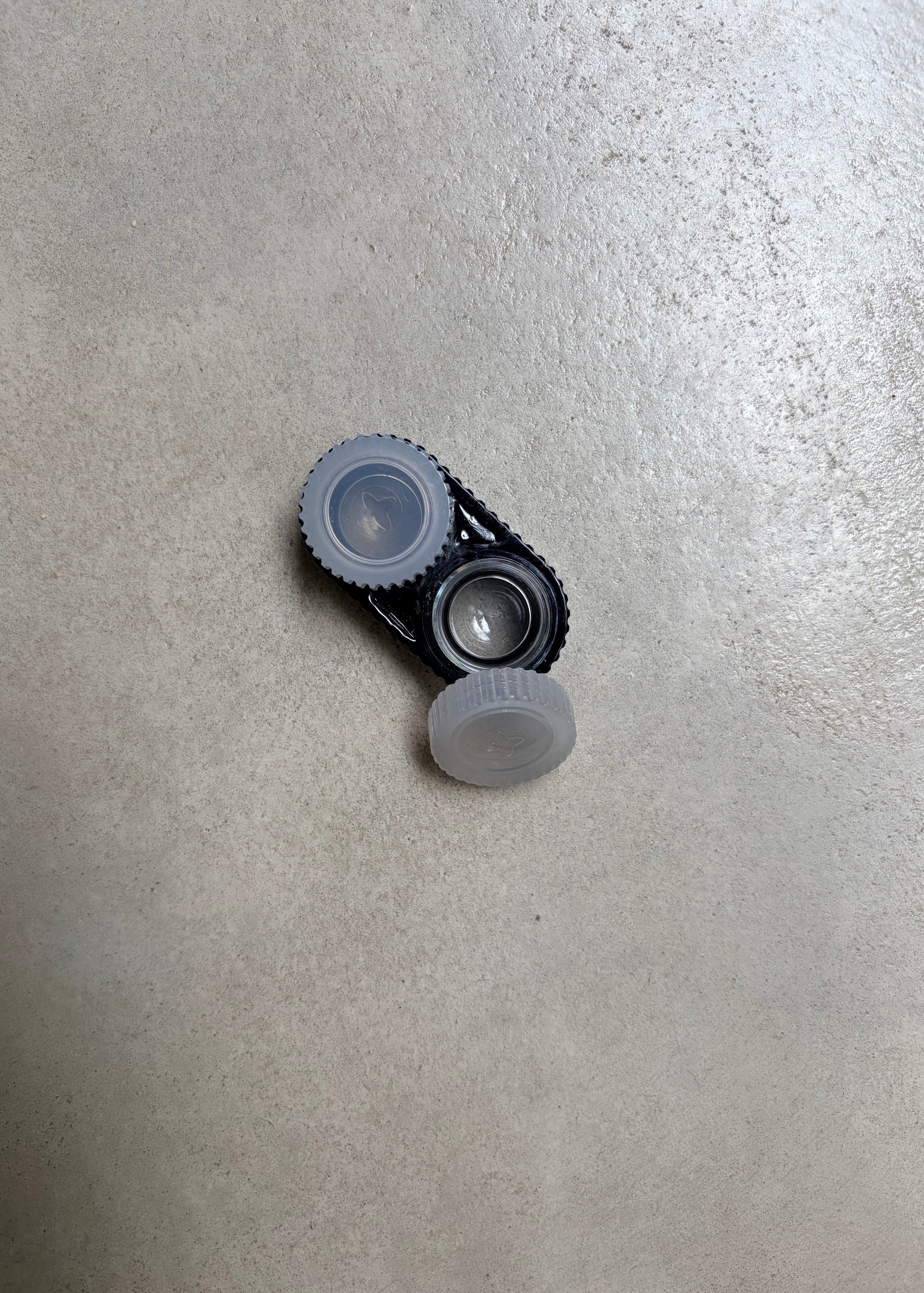 A black contact lens case with white caps, seen from the top